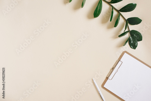 Modern desktop of a freelancer or blogger with a keyboard, mouse, pen and Notepad with a blank sheet of paper on a light beige background with copying space. Flat lay