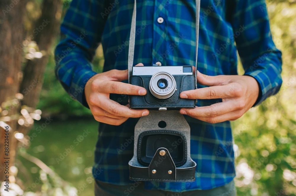 Close up of male photographer hands holding retro camera on green garden background. Close up of male photographer hands holding retro camera on green garden background.
