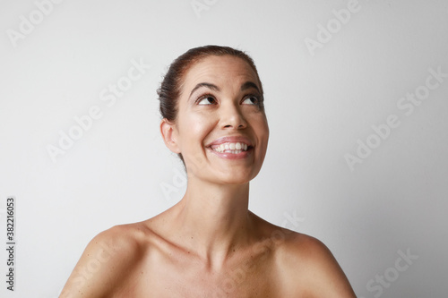 Attractive middle aged European woman looking away with pretty smile isolated over white background. Space for text.