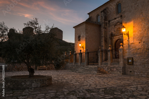 A view of the church of Cogolludo at sunset with the lampposts illuminated and the castle in the background  Guadalajara  Spain