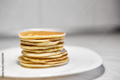 A stack of pancakes is on a white plate