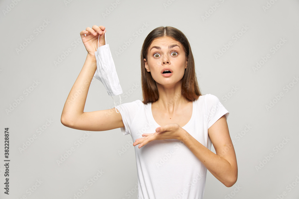 woman With a surprised expression on his face with a medical mask in his hand white t-shirt woman With a surprised expression on his face with a medical mask in his hand white t-shirt