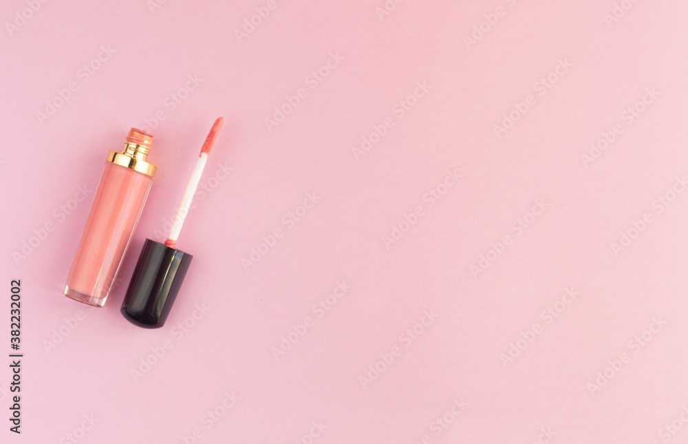 Liquid lipstick and applicator on a pink background. An open tube of lip gloss and a brush stick with makeup on a pink surface. Top view, flat lay, copy space Liquid lipstick and applicator on a pink background. An open tube of lip gloss and a brush stick with makeup on a pink surface. Top view, flat lay, copy space