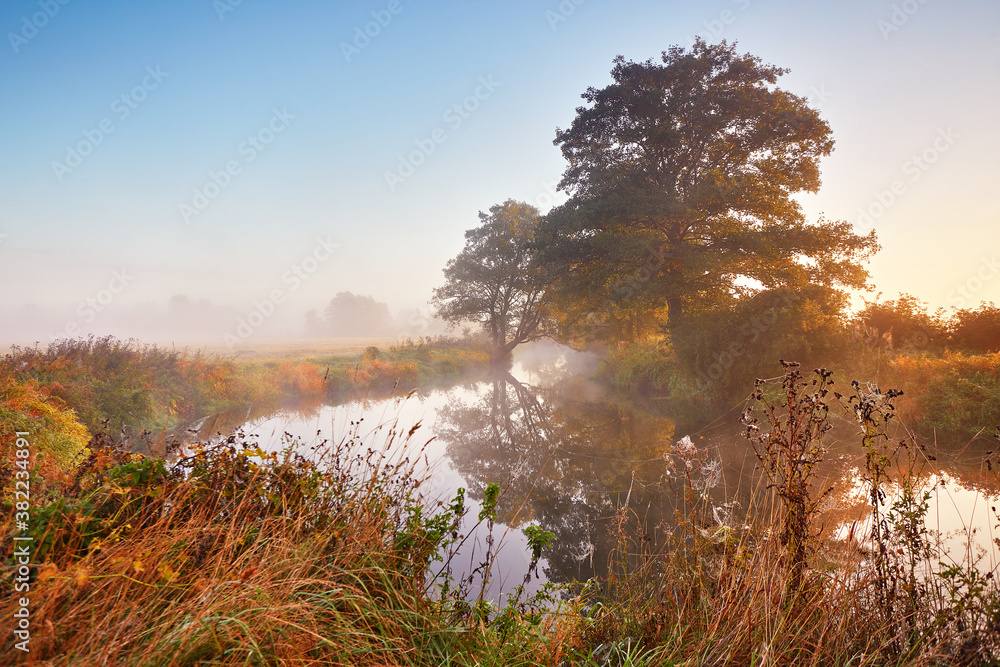 Autumn sunrise rural landscape. Fog on river. October fall calm morning misty scene
