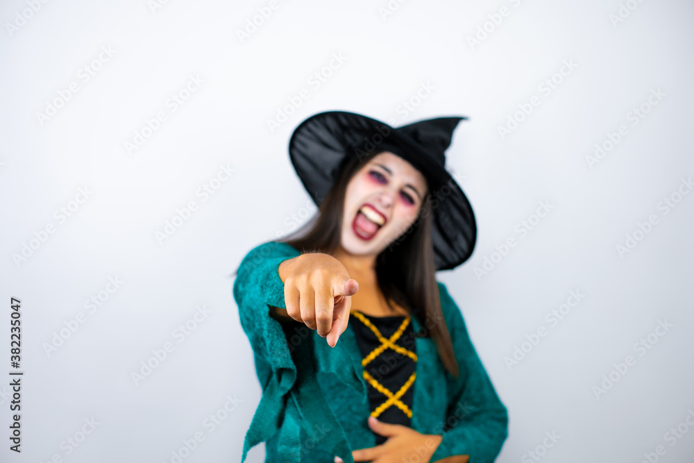 Woman wearing witch costume over isolated white background laughing at you, pointing finger to the camera with hand over body, shame expression