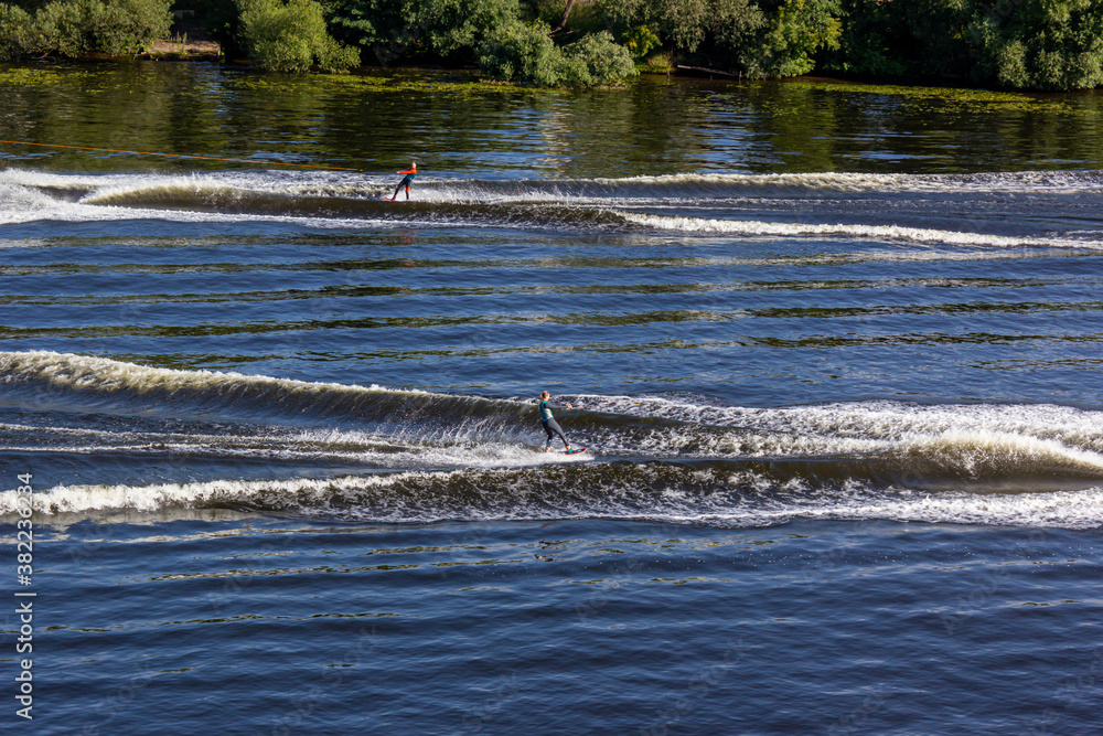 Obraz premium Two athletes on the boards towed behind speed boats meet oncoming courses. Athlete water skiing and having fun. Speed boat for Surfing the Wakeboard. Water skiing on lake behind a boat. Top view