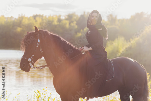 Muslim woman in hijab riding a horse.