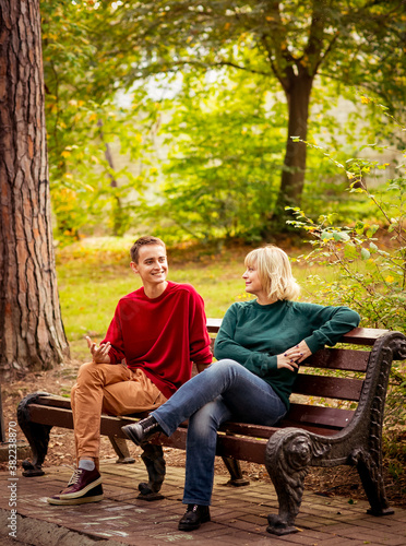 Beautiful woman,blonde,middle-aged,with a big son sitting on a wooden bench in a beautiful Park,Sunny day