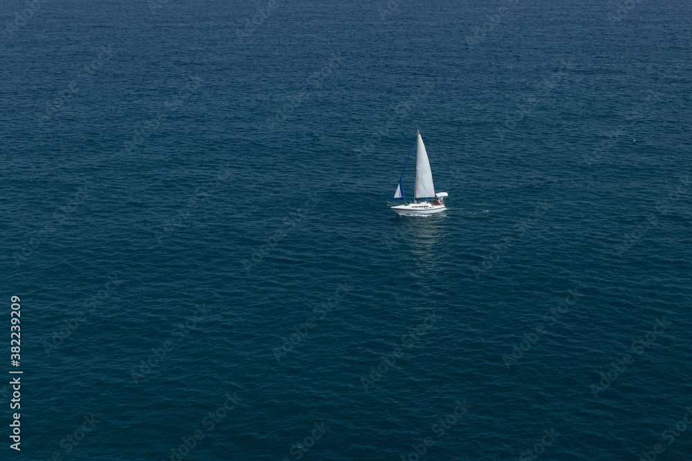 Elegant yacht sailing in still water of an open Mediterranean sea on a clear day. Idyllic seascape. Summer vacations, leisure activity, sport and recreation.