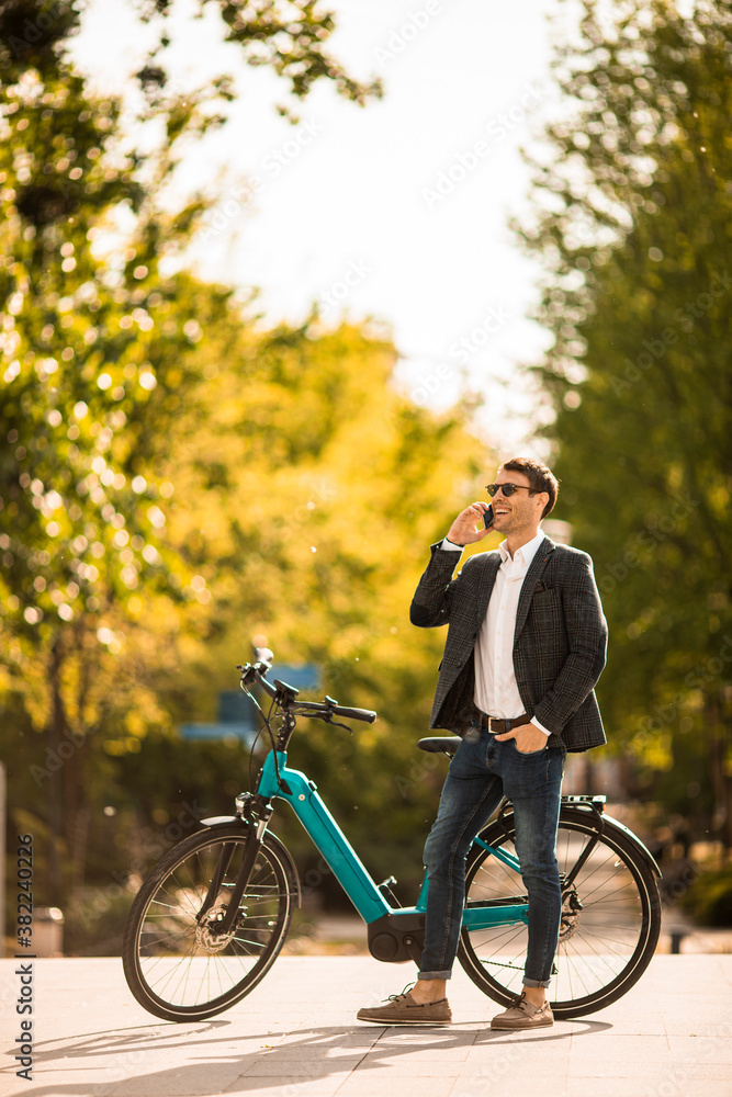 Obraz premium Young businessman on the ebike using mobile phone