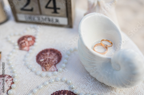 Fotografie Close up view of wedding rings in the white ceramic shell on the table with wedd