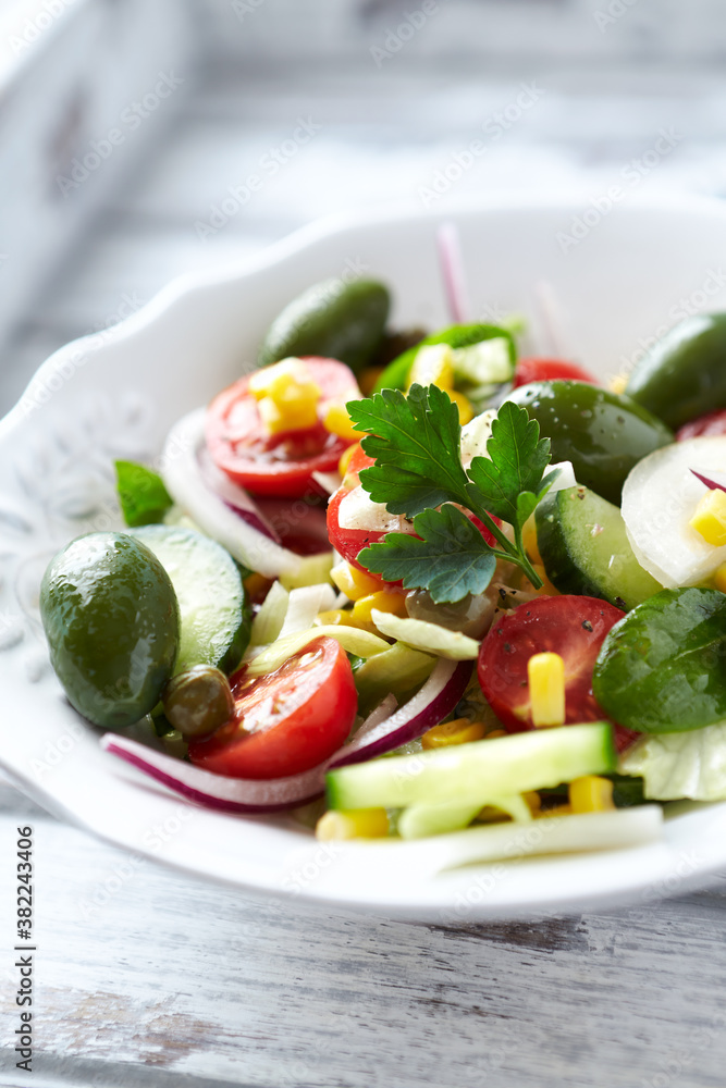 Healthy Salad with Green Olives, Baby Spinach, Cucumber, Cherry Tomatoes and Capers. Bright wooden background. Close up.	