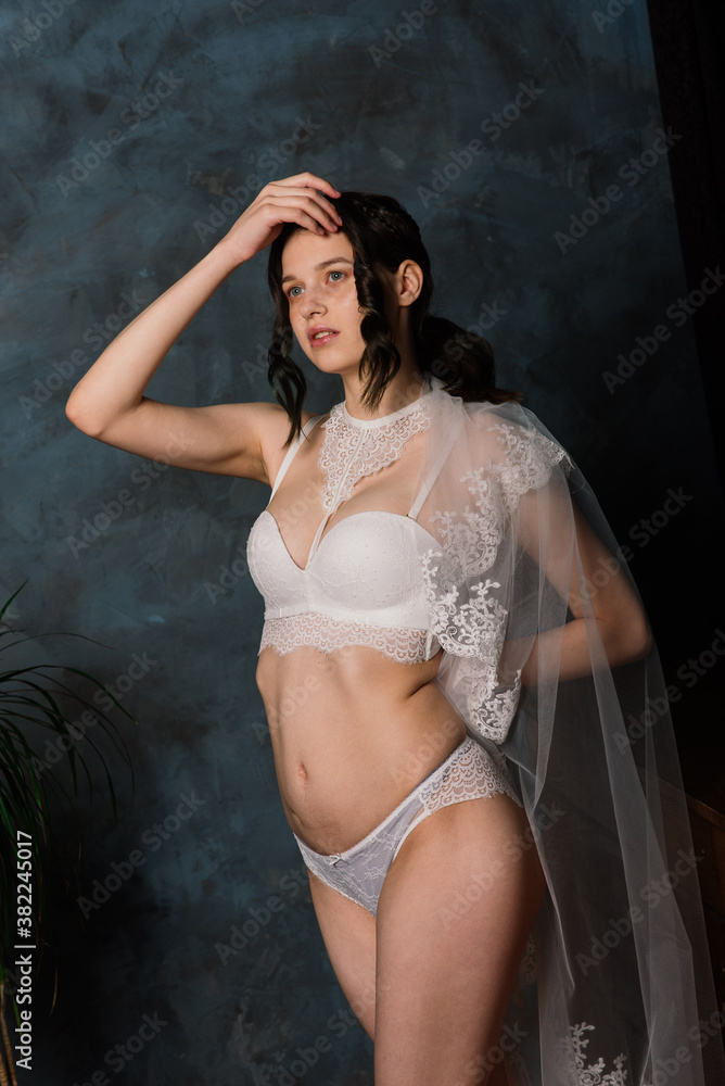 Obraz premium Beautiful bride in white lingerie sitting in her bedroom and studio.