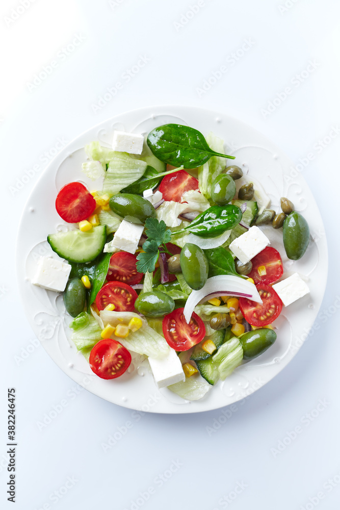 Healthy Salad with Feta Cheese, Green Olives, Baby Spinach, Cucumber, Cherry Tomatoes and Capers. Bright background. Top view. Healthy Salad with Feta Cheese, Green Olives, Baby Spinach, Cucumber, Cherry Tomatoes and Capers. Bright background. Top view.