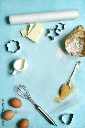 Culinary background with baking paper, whisk and eggs. Top view with copy space.
