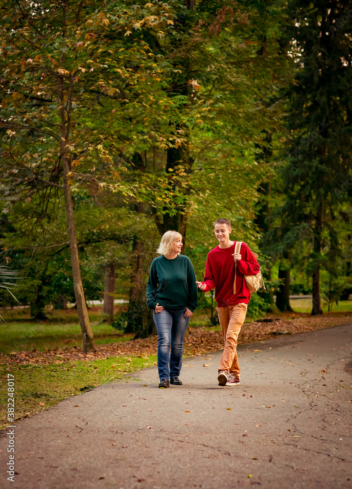 Fototapeta premium Beautiful woman,blonde,middle-aged,with a big son walking in the Park,a beautiful autumn day