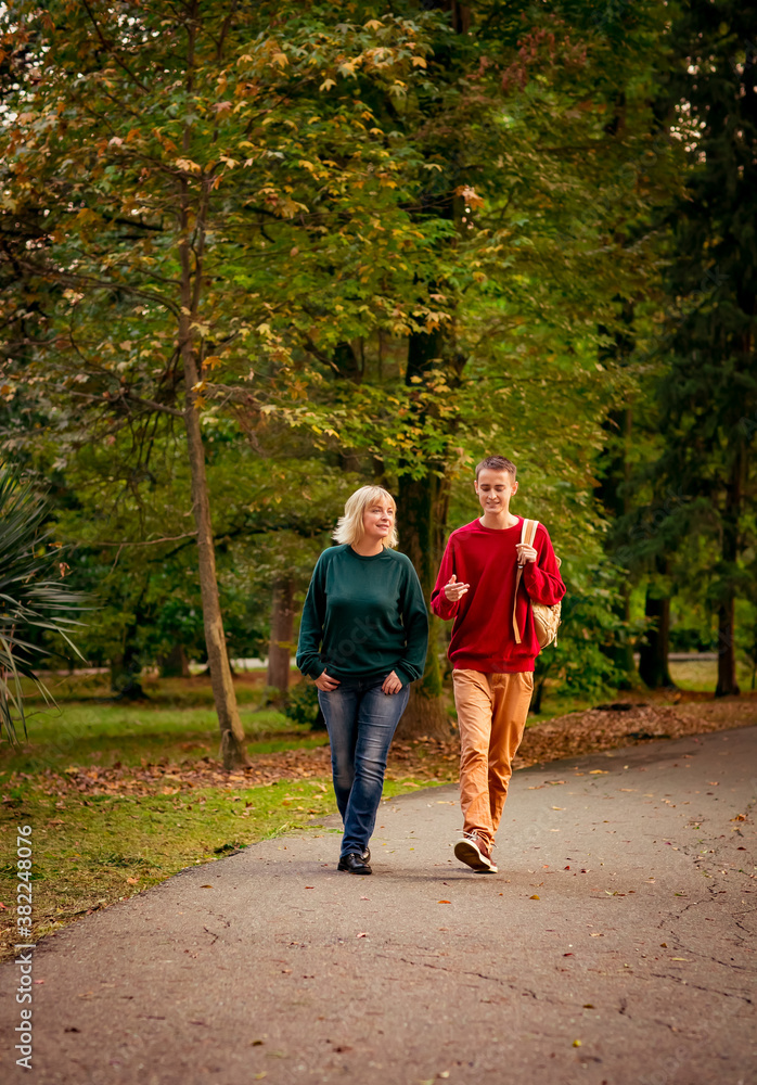 Fototapeta premium Beautiful woman,blonde,middle-aged,with a big son walking in the Park,a beautiful autumn day