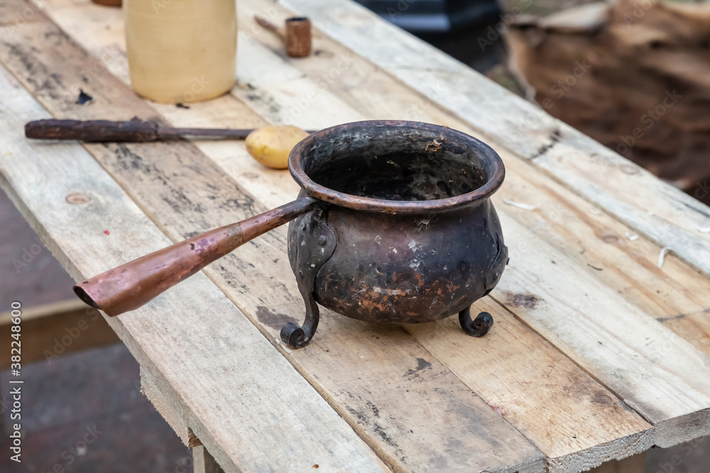 iron three-legged old bowler with a long handle cooking on a fire iron three-legged old bowler with a long handle cooking on a fire