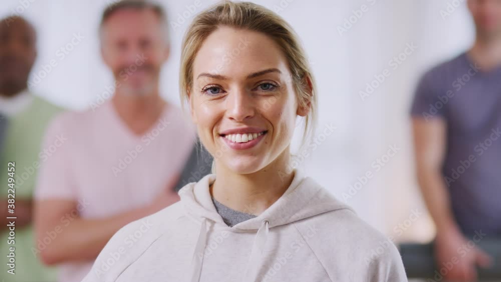 Portrait of female teacher in exercise clothing taking fitness or yoga class in community center - shot in slow motion