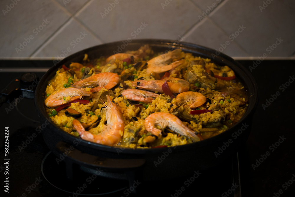 Paella traditional Spanish food. Paella with with mussels, king prawns, langoustine and squids. Person cooking paella.Family dinner.
