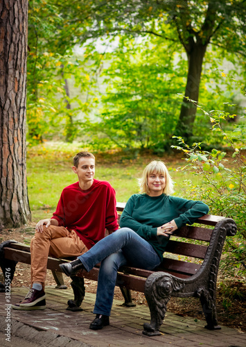 Beautiful woman,blonde,middle-aged,with her son,sitting on a bench and talking