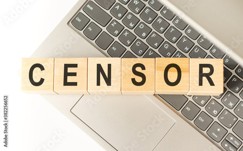 Word censor. Wooden cubes with letters isolated on a laptop keyboard. Business Concept image. photo