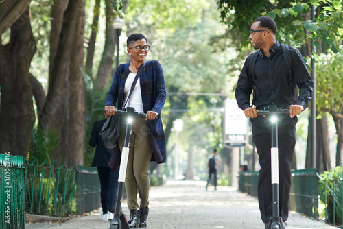 Happy businesswoman on electric scooter talking to a friend photo