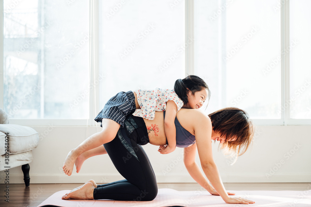 Asian young mom and daughter practicing yoga at home Asian young mom and daughter practicing yoga at home