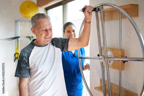 Smiling senior man with an injury doing exercises at a rehab clinic photo