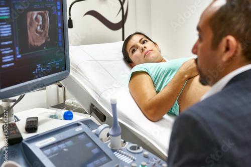 obstetrician doctor doing an ultrasound exam of a pregnant woman photo