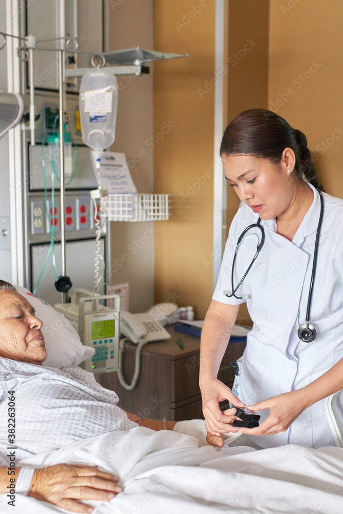 Medical practitioner checking the pulse of an older woman in bed Medical practitioner checking the pulse of an older woman in bed