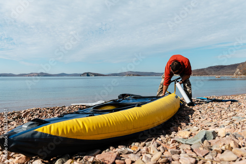 Adult male finishing to pump boat near sea