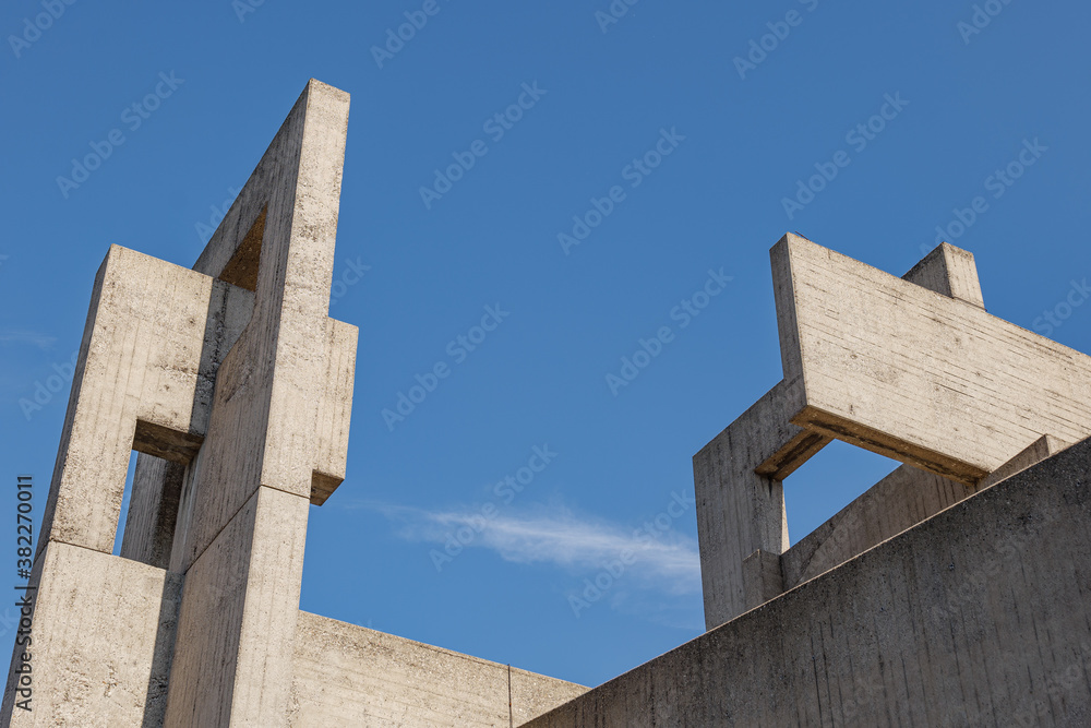 Weird, strange and unique abstract shape and form of concrete Brutalist architecture on the rooftop. Massive solid sculptural building of brutalism style against blue sky.