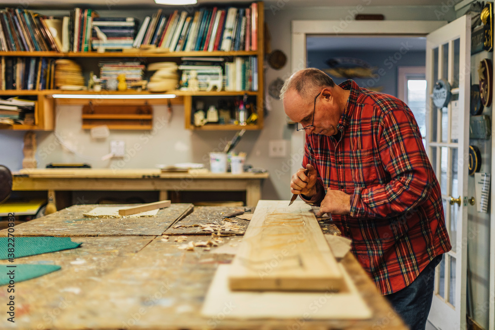 Woodworker at His workshop making a sign Woodworker at His workshop making a sign