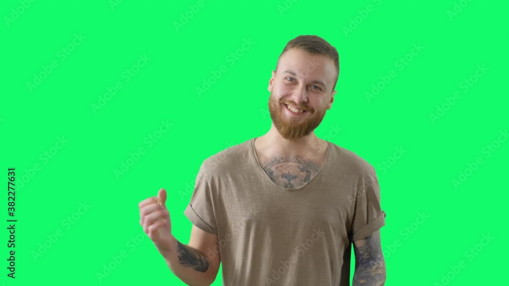 Serious handsome man on chroma key. Happy surprised bearded tattooed hipster is looking to the camera on green screen background. Isolated portrait for keying Serious handsome man on chroma key. Happy surprised bearded tattooed hipster is looking to the camera on green screen background. Isolated portrait for keying