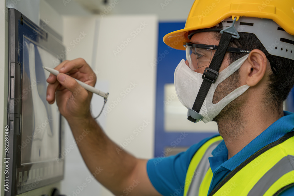 © Mongkolchon - factory worker with face mask working at factory control panel © Mongkolchon - factory worker with face mask working at factory control panel