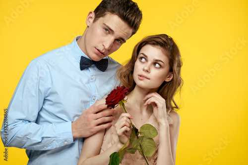 Enamored man and woman with red rose on yellow background cropped view close-up romance