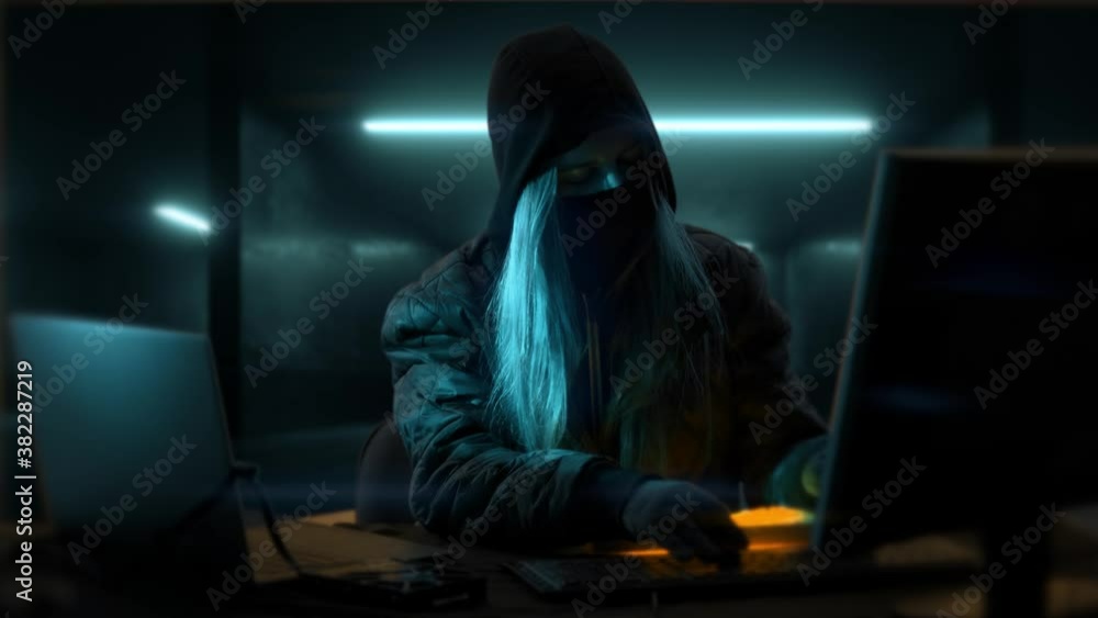 Young anonymous hacker woman with mask. Thief is stealing data from computer or hacking system. Hands in gloves are typing on the keyboard. Theft of cryptocurrency and bitcoin Young anonymous hacker woman with mask. Thief is stealing data from computer or hacking system. Hands in gloves are typing on the keyboard. Theft of cryptocurrency and bitcoin