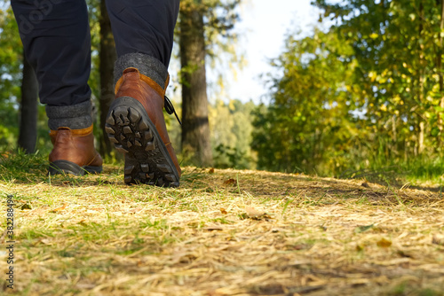 Man hiking in the woods in Autumn pine forest. Men boots walking in the woods on sunny day. hiking concept  outdoor lifestyle.