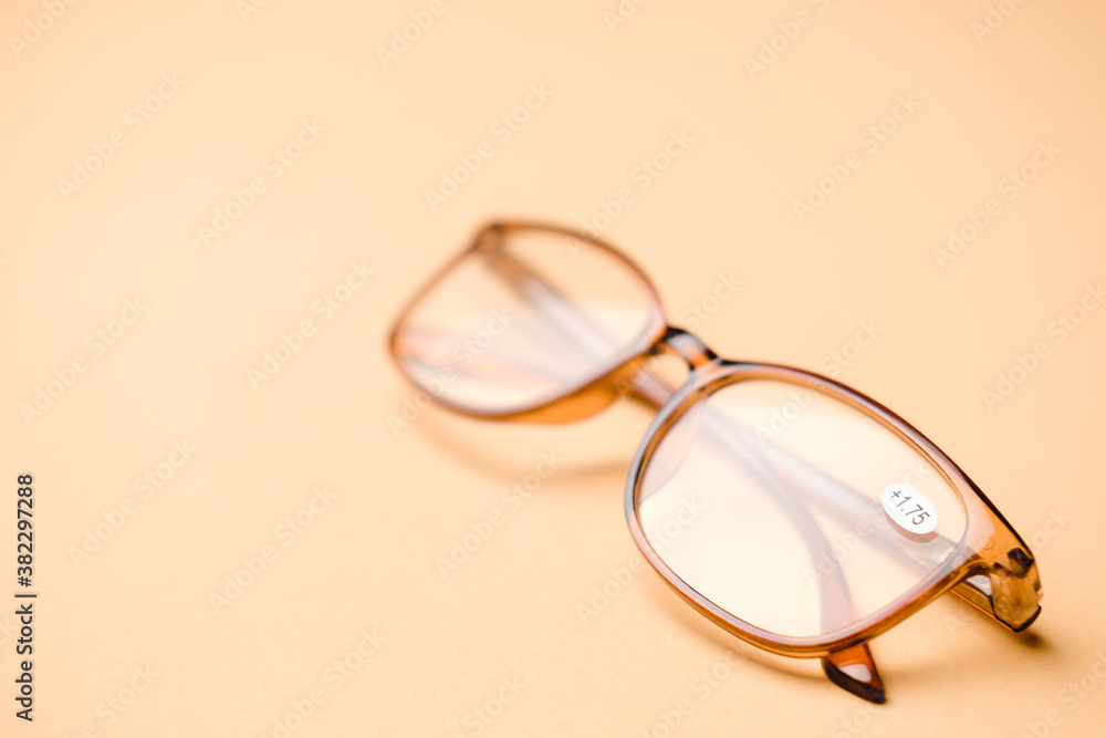 Orange eyeglasses for farsighted people on an orange pastel background. Orange eyeglasses for farsighted people on an orange pastel background.
