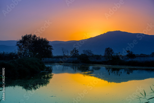 Mountain landscape in the evening. Beautiful lakeshore against mountains. The Hula Valley in northern Israel at sunset