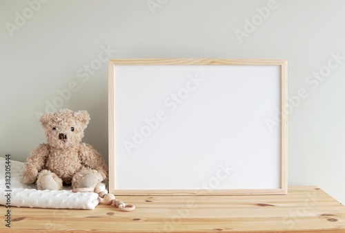 Horizontal wooden frame mockup for neutral nursery to showcase artwork, photo, print, empty frame, toy bear, wooden shelf. photo