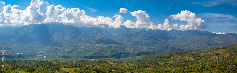 Panorama of wonderful view from Barichara, Colombia over green landscape to mountains with blue sky and white clouds along the mountain ridge