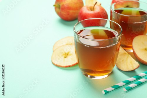 Apple slices, straws and glasses of apple juice on mint background
