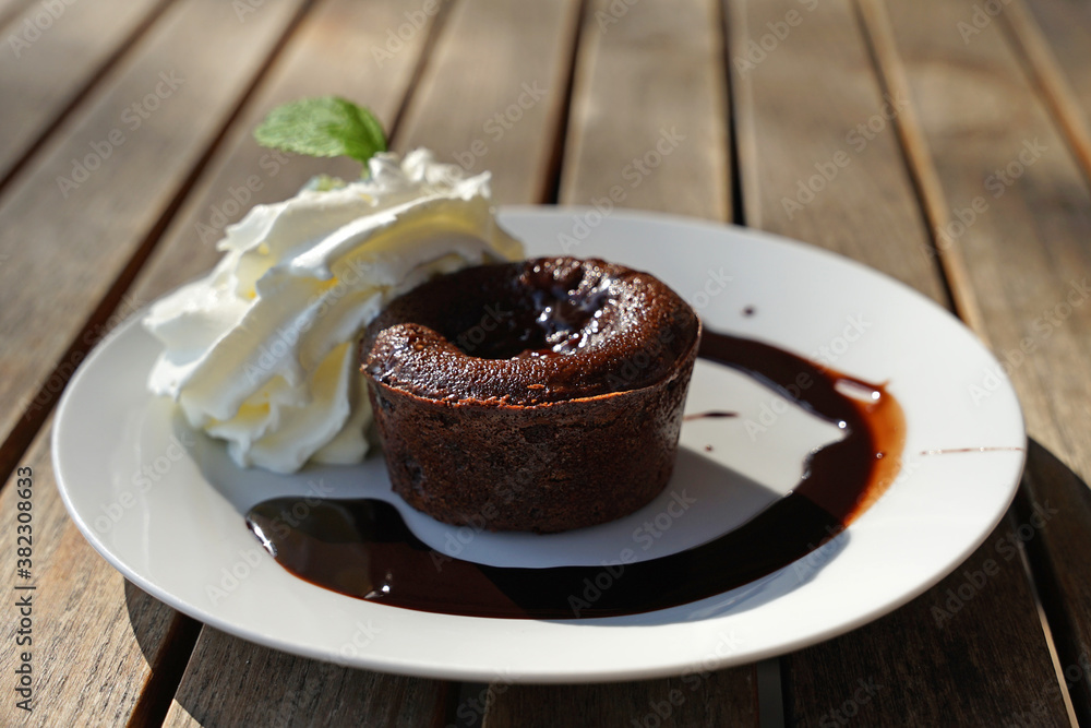 Tasty sweet chocolate souffle with warm sauce and cream on terrace garden table, popular modern desert served in many cafes Tasty sweet chocolate souffle with warm sauce and cream on terrace garden table, popular modern desert served in many cafes