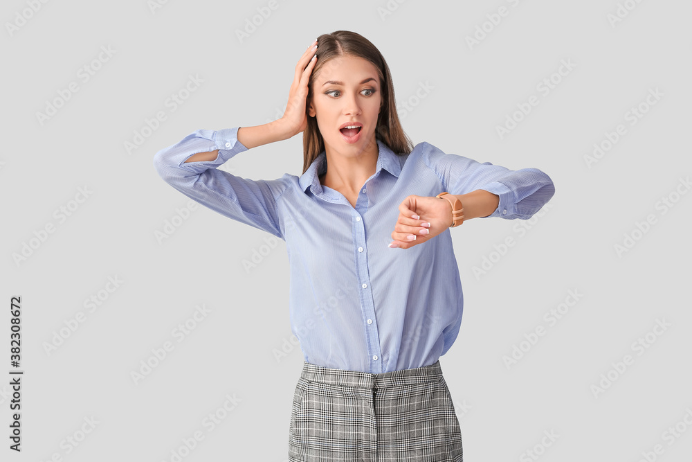 Shocked young woman with wristwatch on light background Shocked young woman with wristwatch on light background