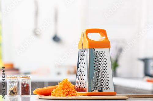 Metal grater and carrot on kitchen table