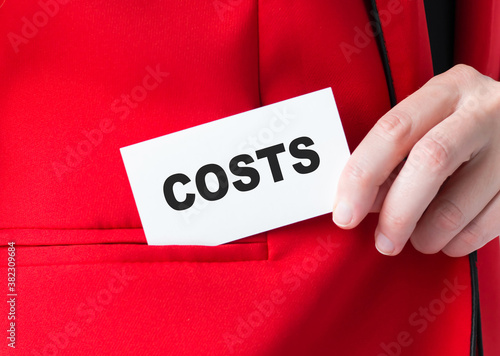The word COSTS on a card in the hands of a businessman in a carnom jacket close up, business concept