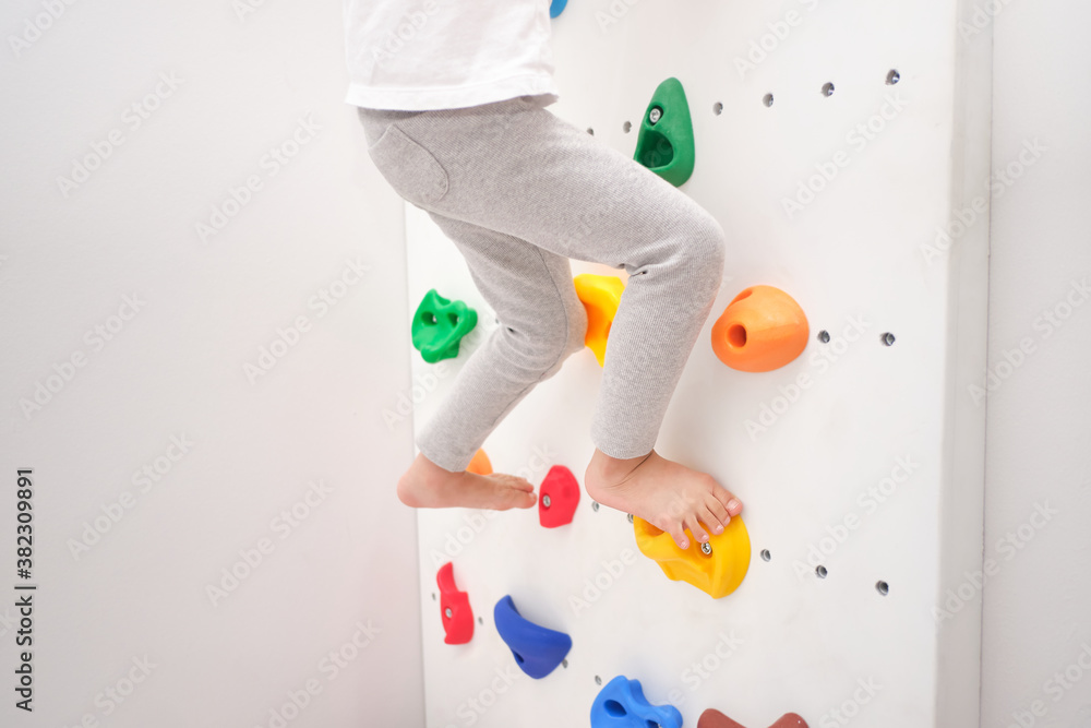 Φωτογραφία Close up of legs of little kindergarten boy having fun trying to climb on a smal