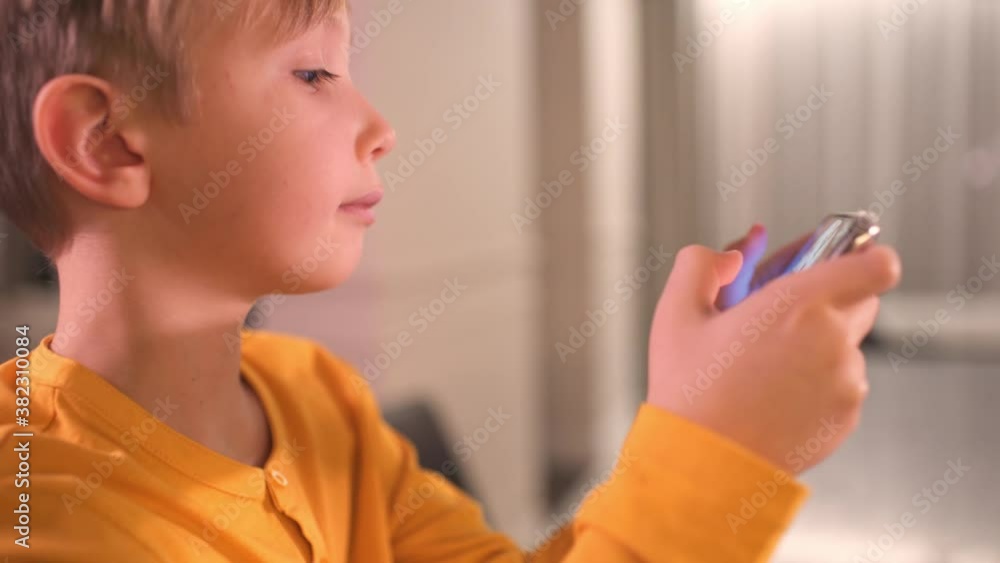 Close up face of a boy with smartphone, at home. Caucasian child spending time in a social network using mobile phone. White kid using cell phone for gaming. Lifestyle concept. Full HD footage. Close up face of a boy with smartphone, at home. Caucasian child spending time in a social network using mobile phone. White kid using cell phone for gaming. Lifestyle concept. Full HD footage.